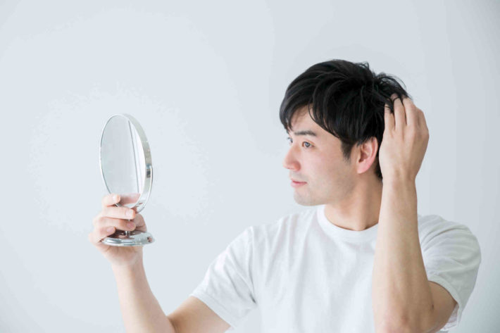 手鏡で髪型をチェックしている男性