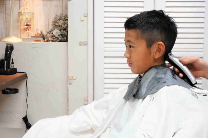 髪を家族に切ってもらっている男の子