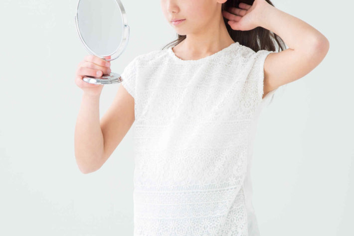 鏡を見ながら髪を触っている女性