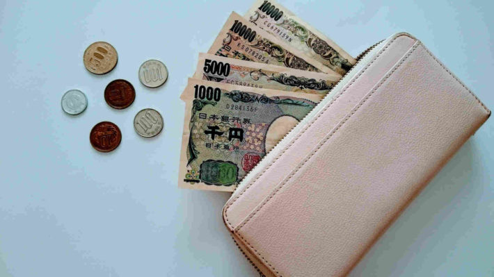 女性物のラウンドジップ長財布からお札とコインが出ている画像