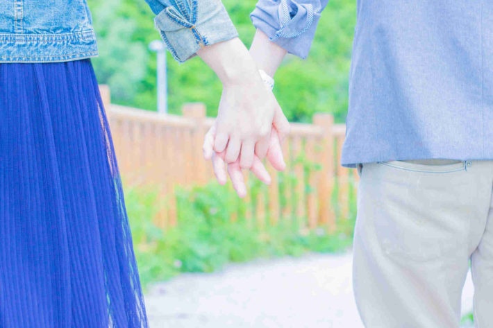 手を繋ぎ合う男女の後ろ姿