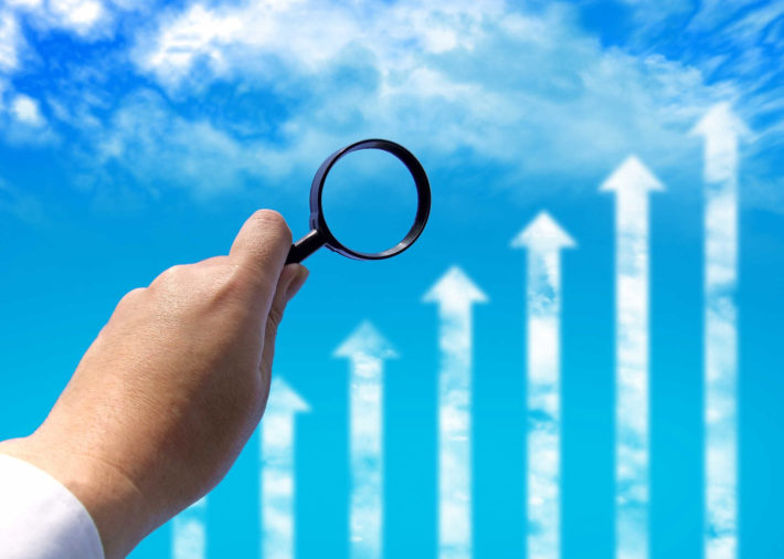 空に浮かんだグラフとそれを見る虫眼鏡