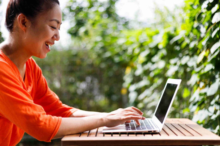 野外でノートパソコンを使い仕事をしている女性