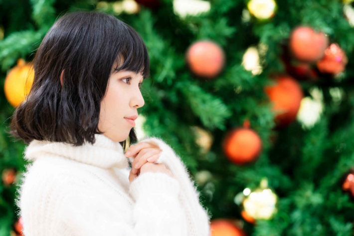 クリスマスツリーの前で誰かを待っている女性