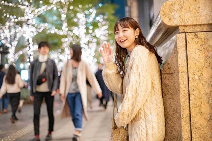 イルミネーションの街中で誰かを待っている女性