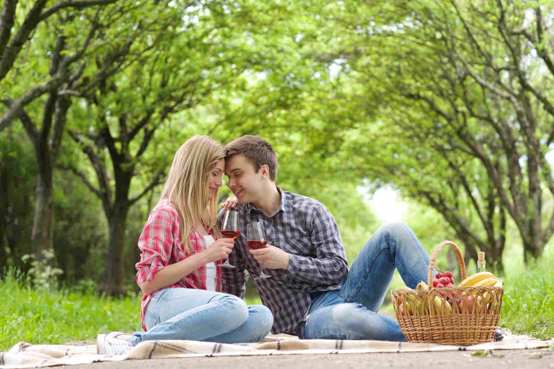 野外で広げたシートの上に座り、ワインを飲んでいる外国人の男女