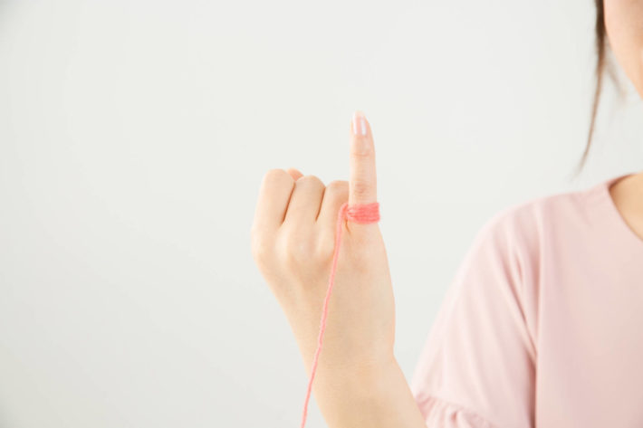 小指に赤い糸が巻かれている女性
