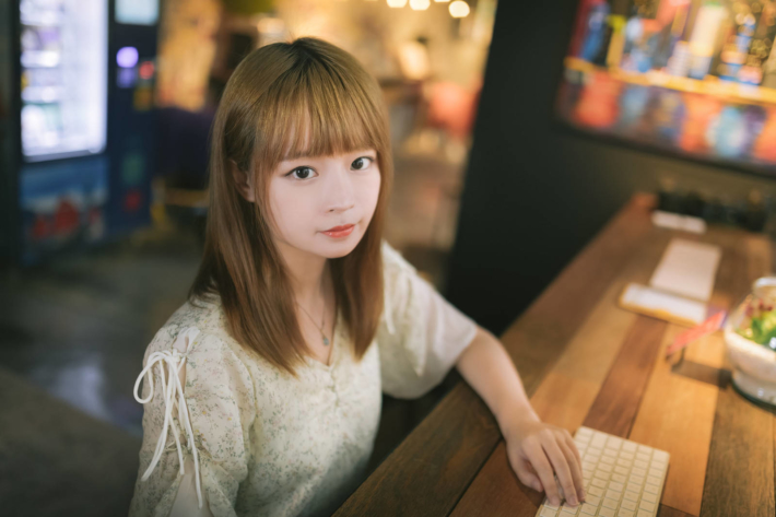 木のテーブルに肘を付け、付属のキーボードを使っている女性