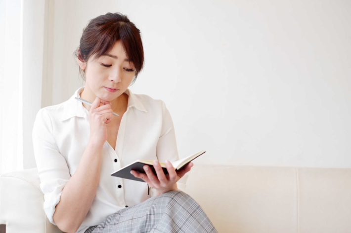 ノートを見て考え事をしている女性