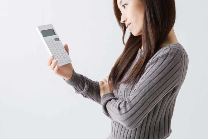電卓を片手に悩んでいる女性