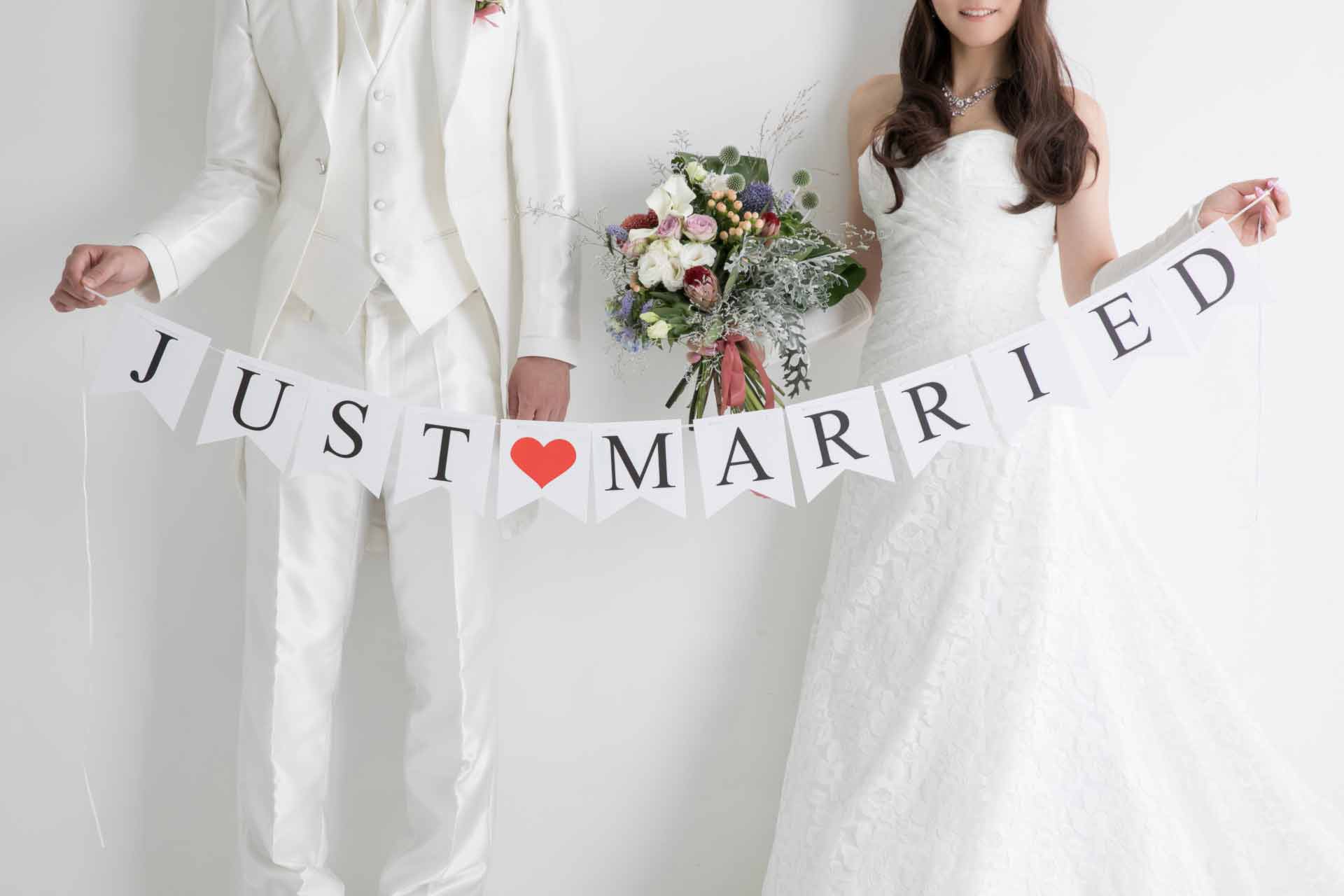 「JUST MARRIED」のオーナメントを持つ正装した男女のカップル