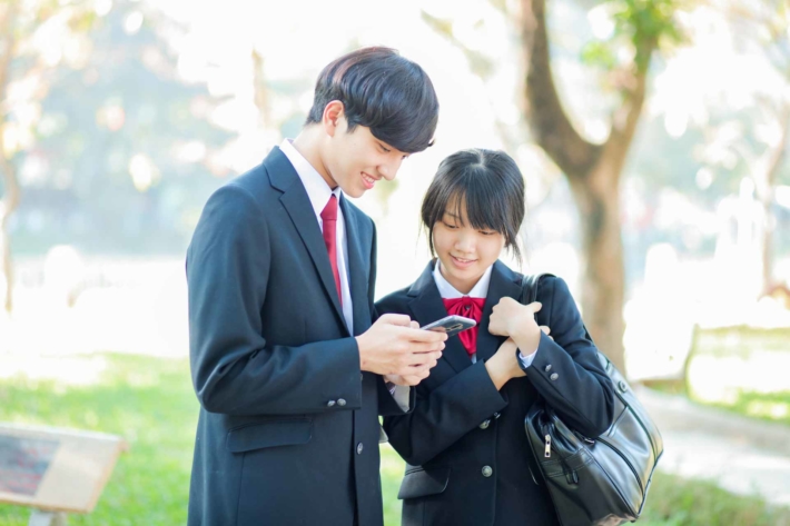 男子のスマホをのぞき込む女子高生