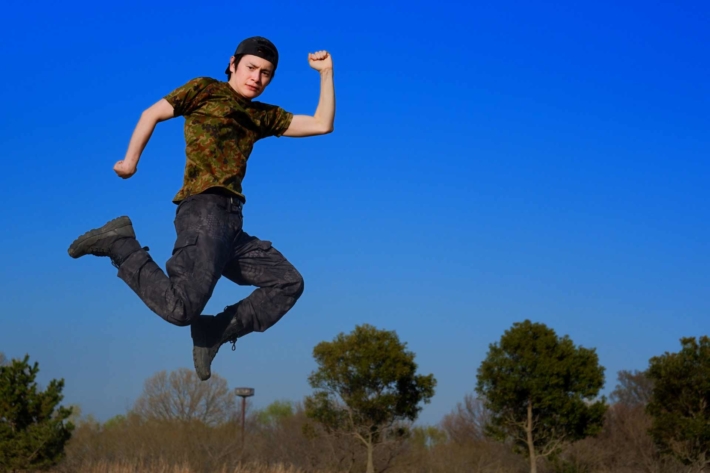 青空を背景にジャンプしてポーズをキメている男性