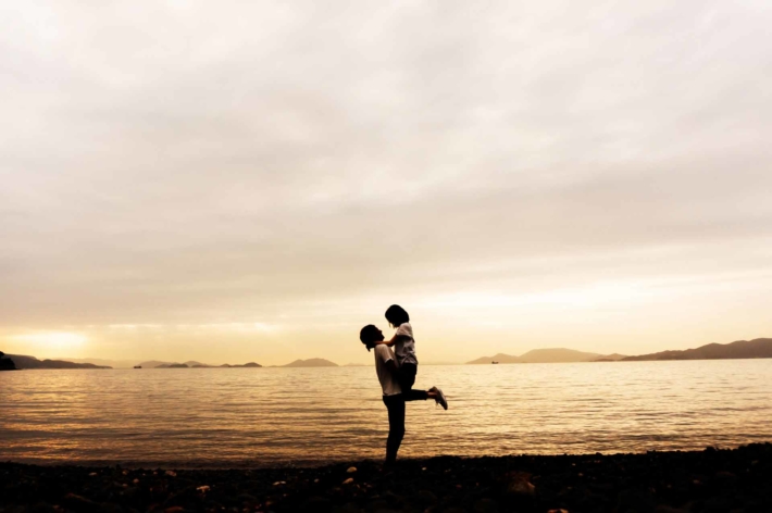 沈む夕焼けを背景に抱きしめ合うカップル