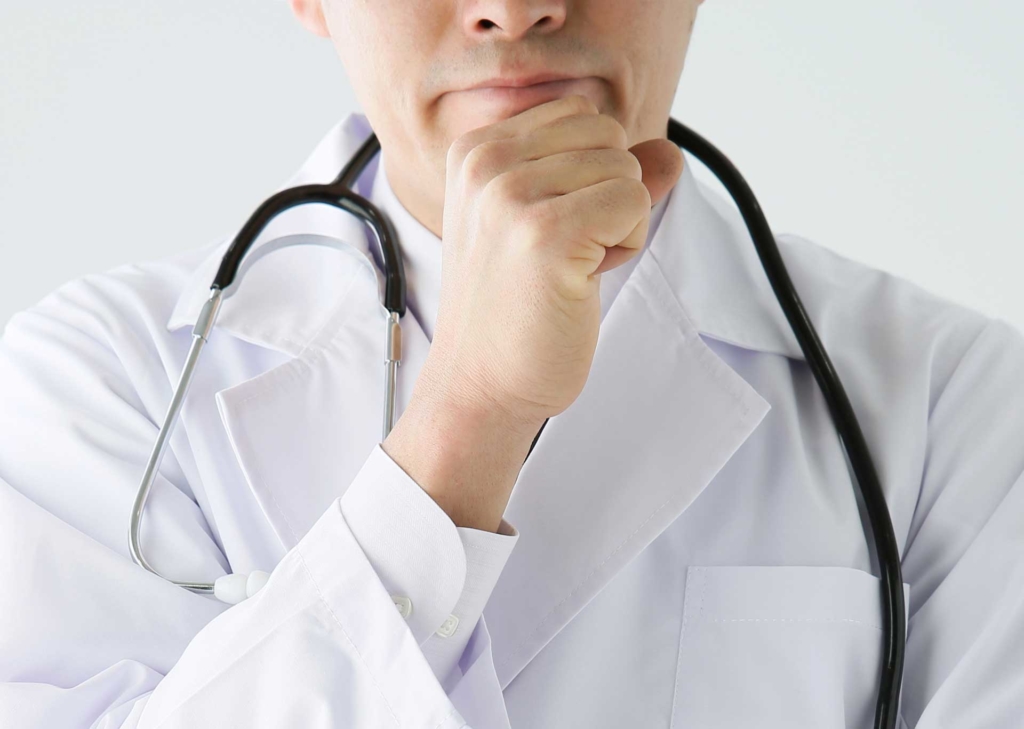 顎に手をあてて考え込む医者