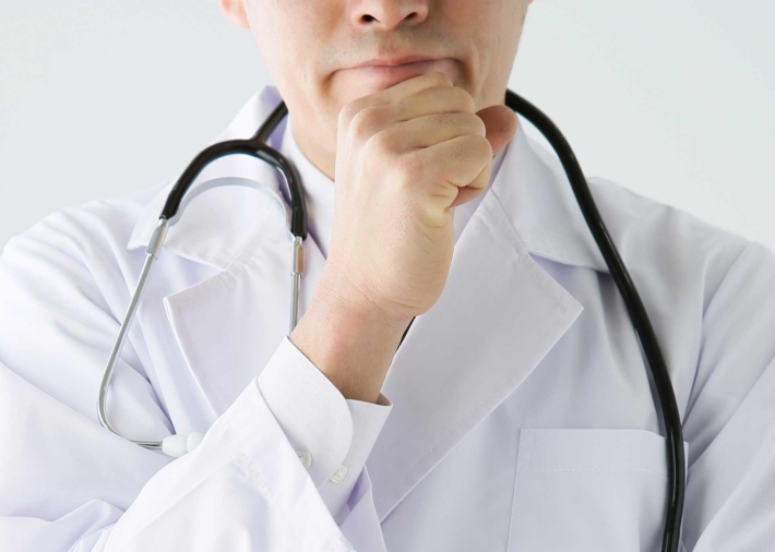 顎に手をあてて考え込む医者