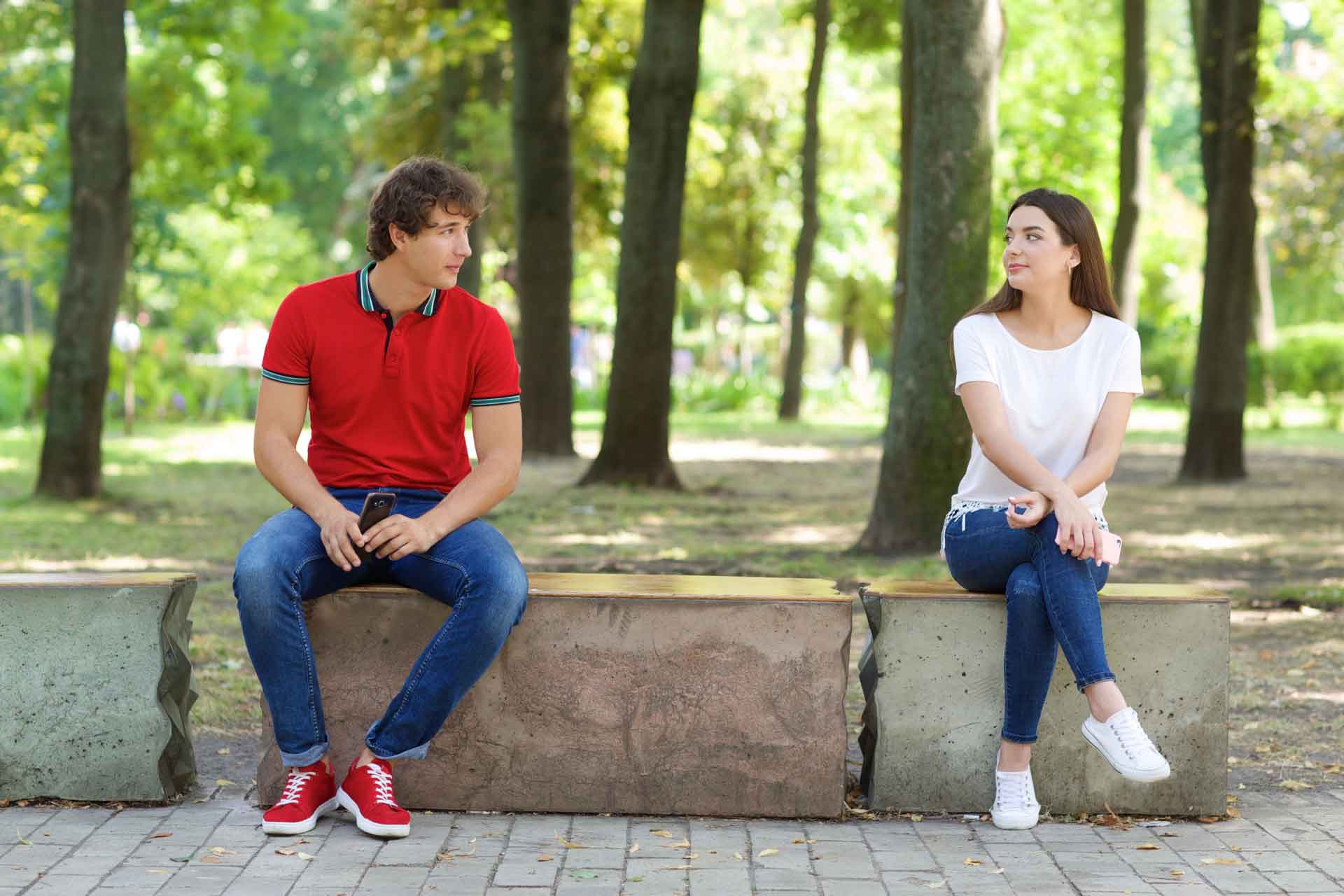 公園で離れて座る男女のカップル