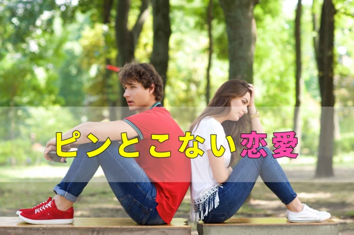 ピンとこない恋愛の文字と公園に背中合わせに座る男女