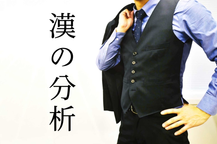 「漢の自己分析」と書かれたテキストに手に腰をあてて立つベスト姿の男性