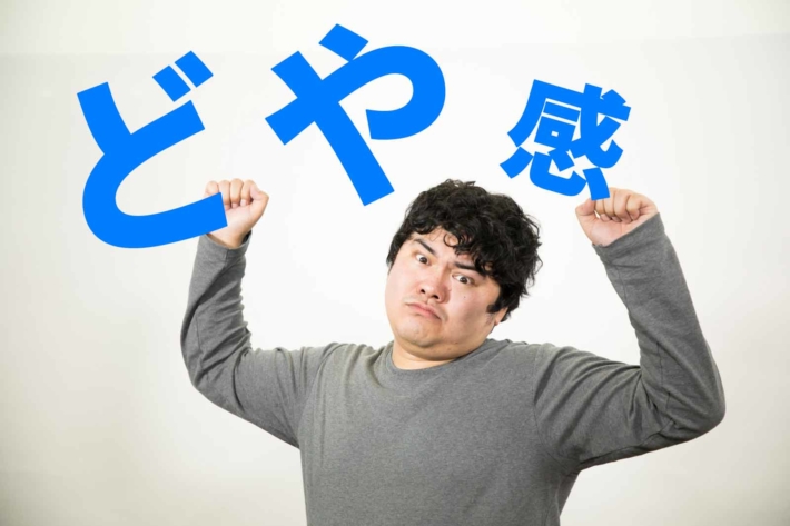 「どや感」と書かれたテキストと両腕を上げてポーズを取りイキっている男性