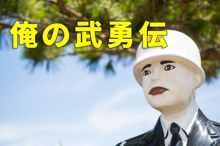 「俺の武勇伝」と書かれたテキストに空を見つめる警察官の人形