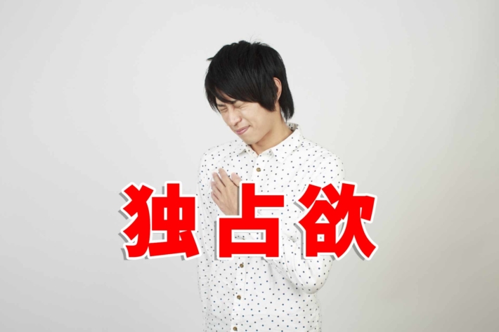 「独占欲」と書かれたテキストと、胸を痛めしかめっ面の男性