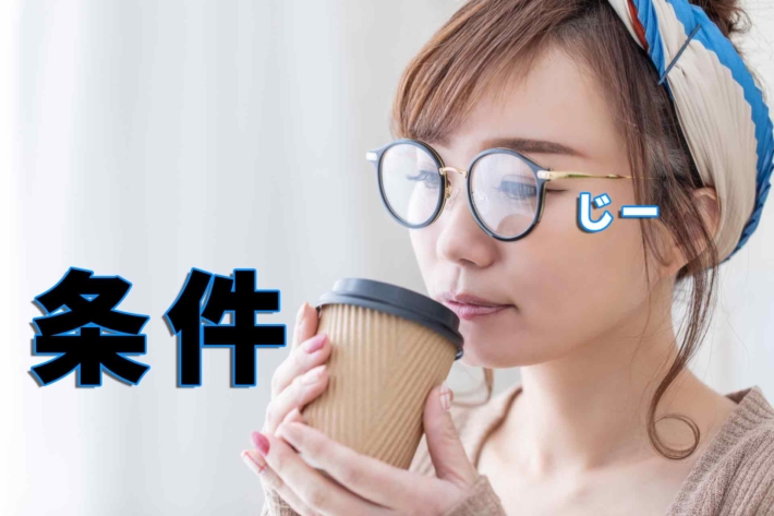 「条件」をお茶を飲みながらじーっと見つめるメガネの女性