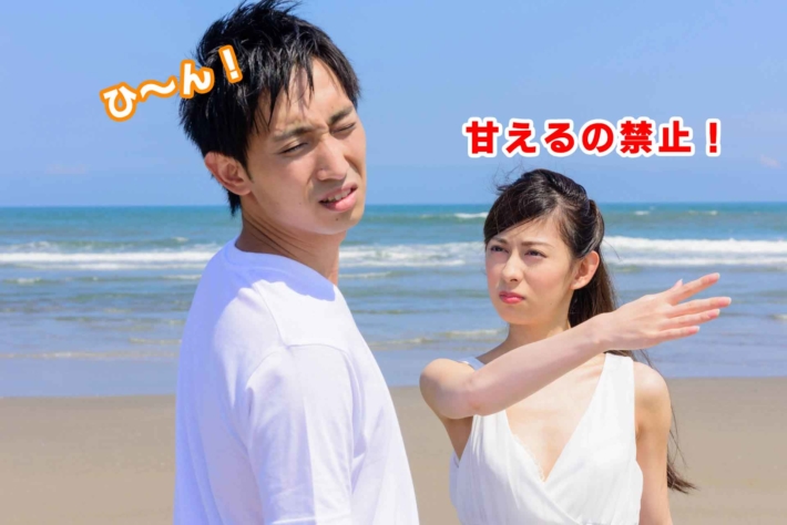 「甘えるの禁止!」と書かれたテキストと、砂浜で男性にビンタしている女性