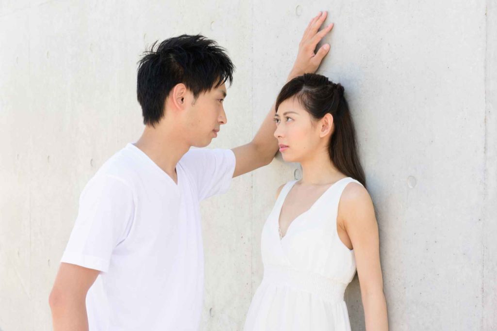 壁ドンして女性を見つめている男性
