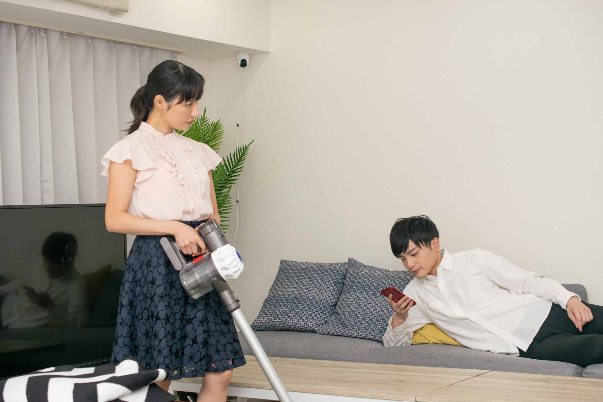 ソファーでゴロゴロしている男性を睨む女性