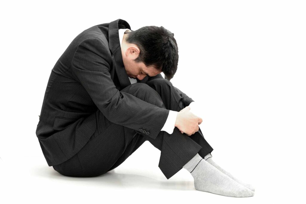膝を抱えてうつむく男性