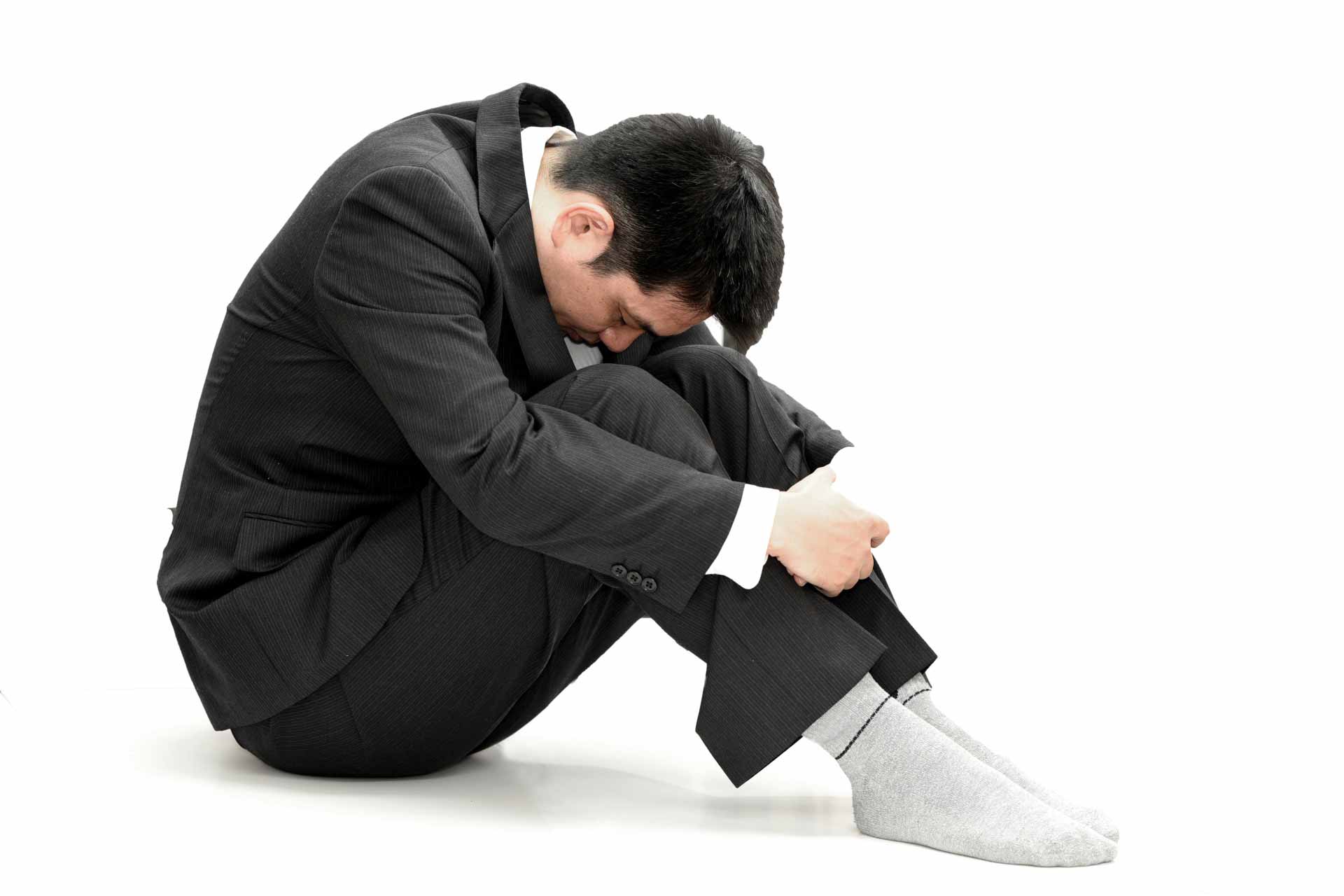 膝を抱えてうつむく男性