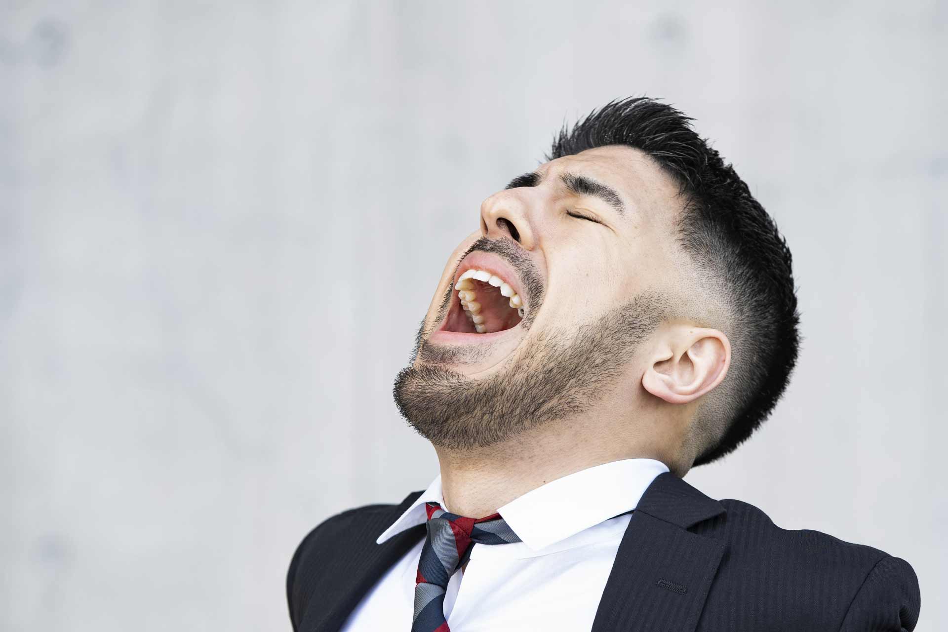 口を大きく広げて何か叫んでいる様子のサラリーマン