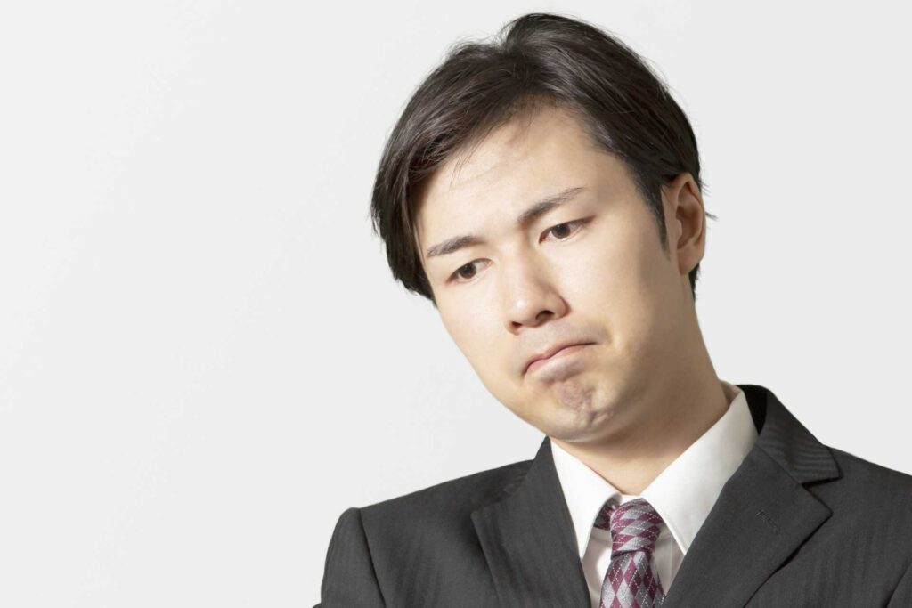 顔を強張らせて下を向いている男性
