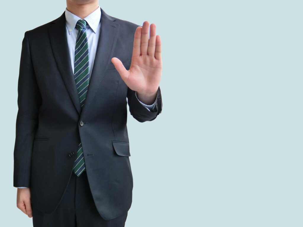 手を前に出し拒否するポーズのサラリーマン