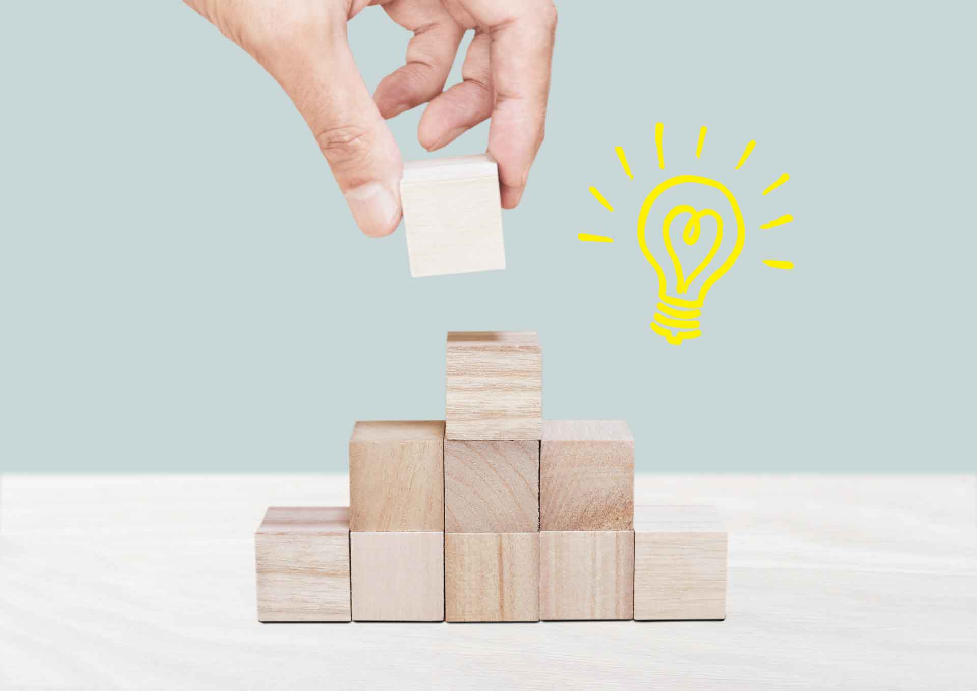 ブロックを積んでいる手と、ピラミッド型に積み上げられたブロック