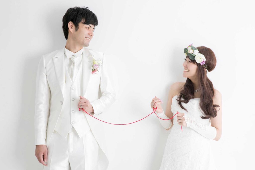 小指を赤い糸で繋がれた新郎と新婦