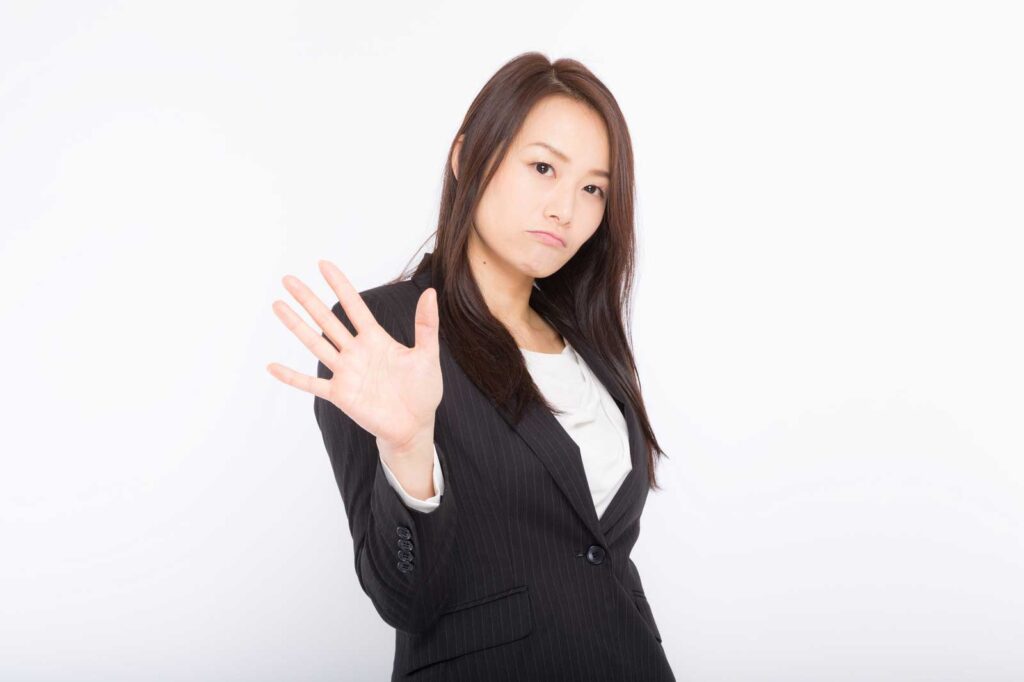 手を前に出し相手を制しようとしている不機嫌そうな顔の女性