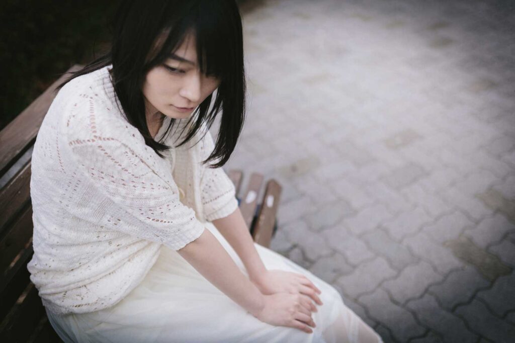 公園のベンチで俯いている女性