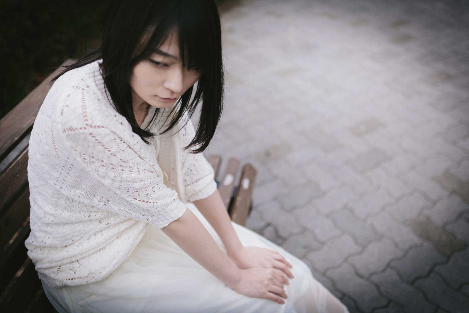 公園のベンチで俯いている女性