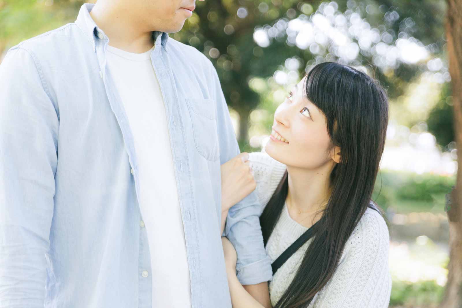 男性の左腕を持って腕組しながら、男性の顔を覗き込んでいる女性