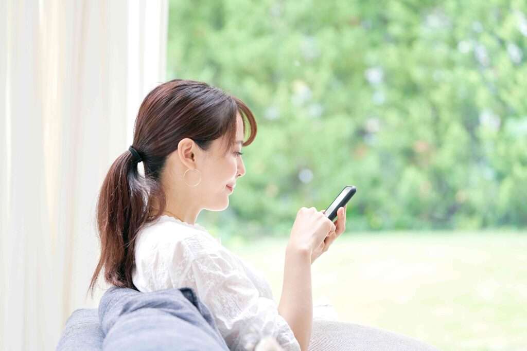 ソファーに座りスマホを使う女性の横顔
