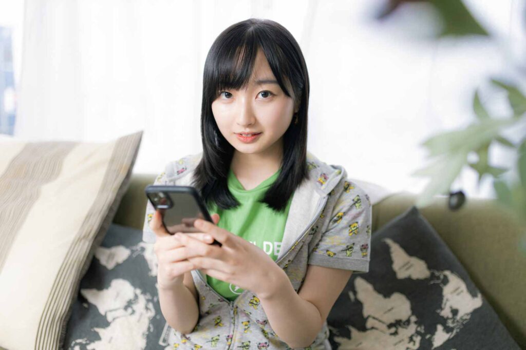 スマホを持って上目遣いでこちらを見ている女性