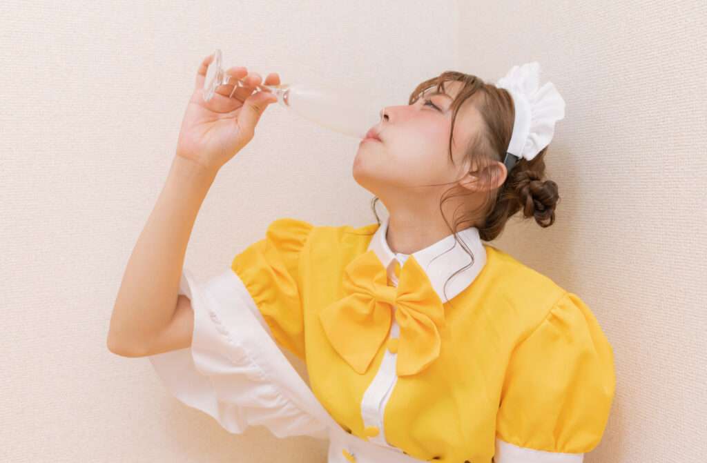お酒を一気飲みしているメイド服姿の女性