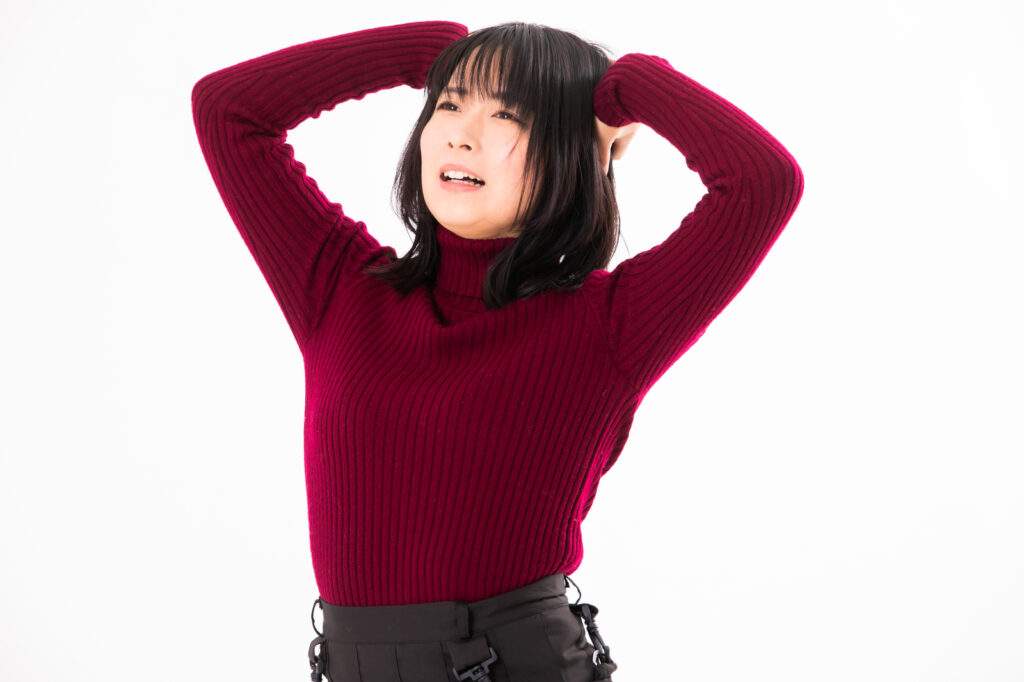 頭を抱える赤いニットセーターの女性