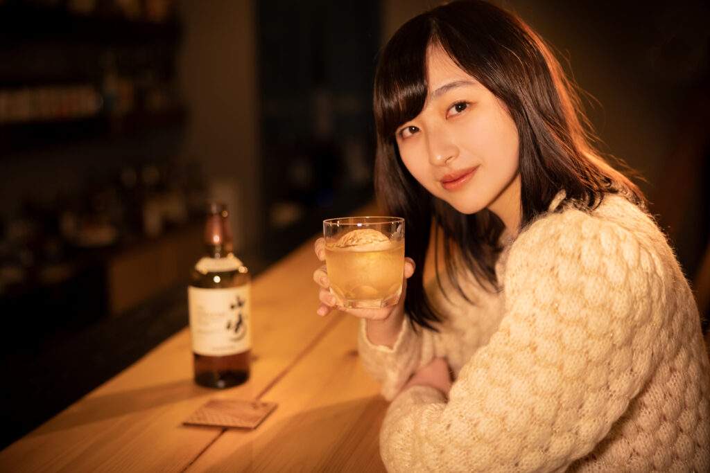 BARカウンターで酒を飲みこちらに微笑む女性