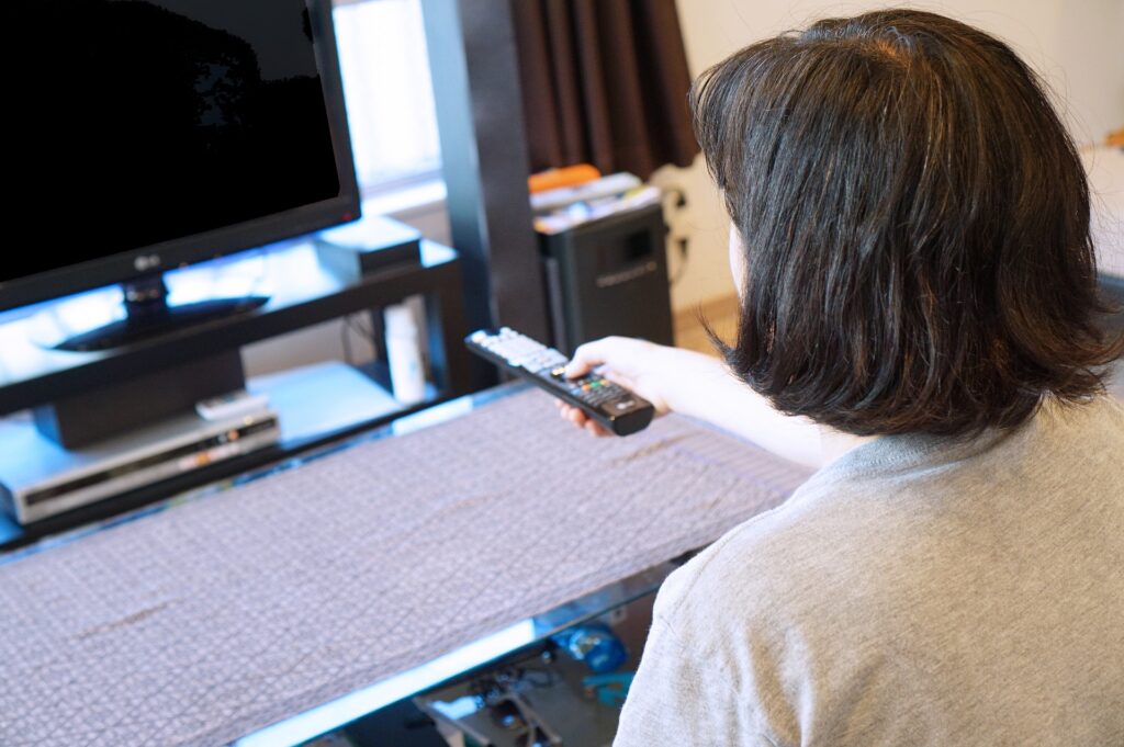 テレビを点けようとしている50代ぐらいの女性後ろ姿