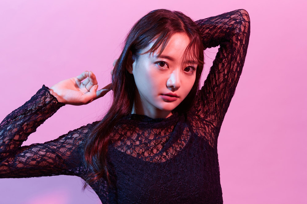 両腕を頭の後ろに回してポーズをとっている韓国メイクの女性