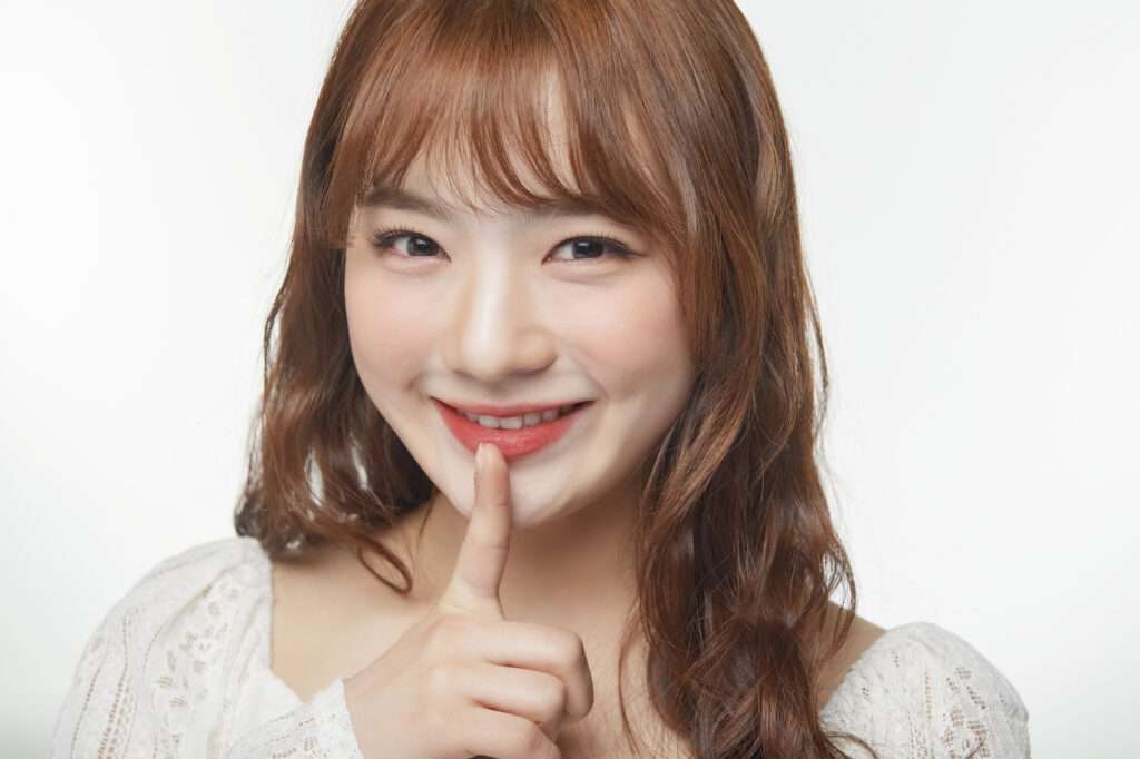 唇に人差し指をあてている笑顔の女性