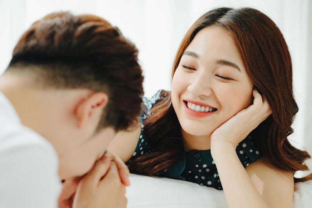ベッドで女性の手にキスをする男性